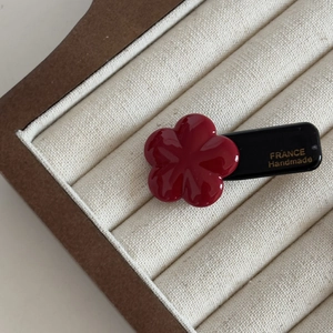 Detail of red floral acetate hair clip with France Handmade gold lettering