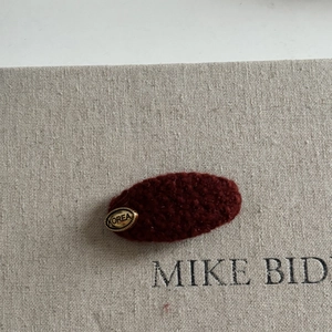 Detailed texture of dark red woolly hair clip with a gold metal Korea logo tag