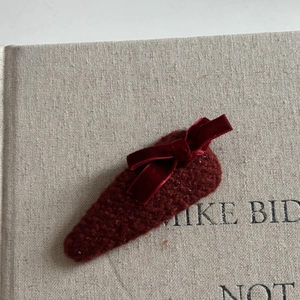 Macro view of wine red woven hair clip with velvet bow on textured grey surface