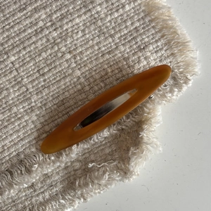 Macro view of matte amber acetate hair clip with oval cutout and metal spring mechanism