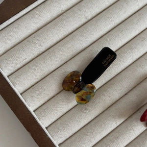 Detail of a handmade tortoise shell hair clip on a white fabric display tray