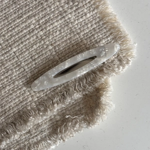 Close-up of white marble acetate hair clip with hollow oval design in French style