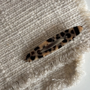 Close-up of tortoise shell pattern on oval acetate hair clip with metal base