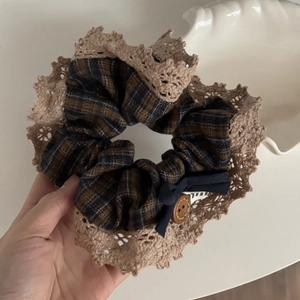 Détail d'un chouchou à carreaux avec dentelle beige, nœud bleu et bouton en bois