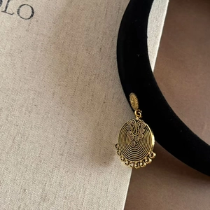 Detailed close-up of a vintage golden hollow circular earring with ethnic carving details