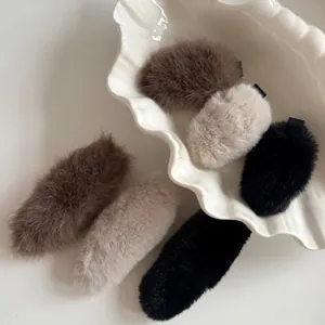 Barrettes en fausse fourrure pelucheuse marron, beige et noire sur assiette blanche