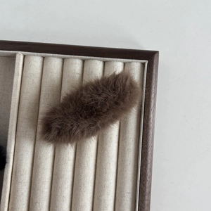 Vue détaillée d'une pince à cheveux en peluche marron foncé sur un plateau à bijoux