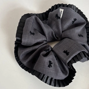 Detail of dark grey scrunchie with bow patterns and pleated black lace edges