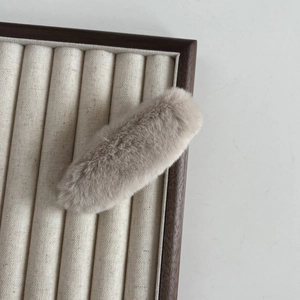 Gros plan sur une barrette en peluche douce beige sur un plateau de bijoux en bois massif