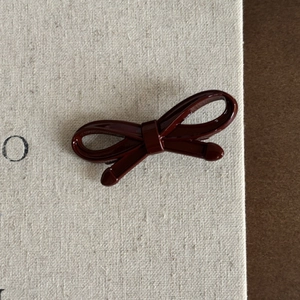 Gros plan détaillé d'une pince à cheveux nœud rouge bordeaux avec finition émaillée brillante
