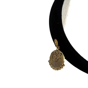 Vintage gold ethnic earrings with spiral carvings displayed on a black velvet headband