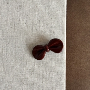 Détail d'une pince à cheveux nœud rouge foncé avec finition brillante sur lin