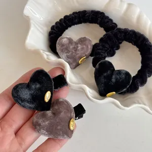 Close-up of velvet heart hair ties and clips with gold 'Love' charms in a shell tray