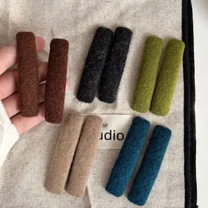 Close-up of colorful felt-wrapped rectangle hair clips in five earthy autumn tones