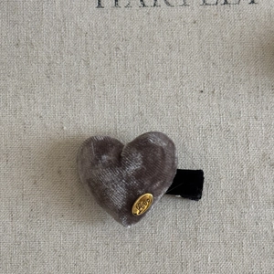 Elegant grey velvet heart hair clip with gold Love metal logo on beige canvas background