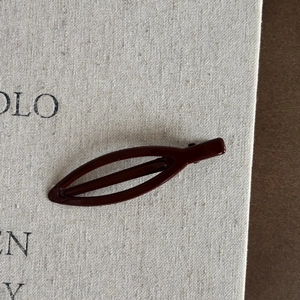 Détail macro d'une pince à cheveux en métal rouge bordeaux avec finition polie brillante