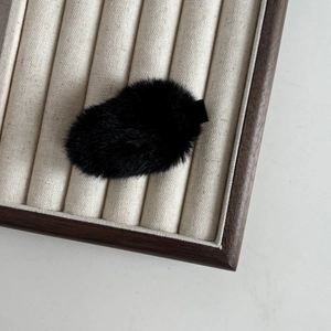 Gros plan sur la texture de la barrette en peluche noire et sa structure sur un plateau
