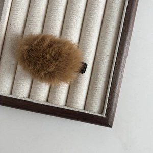 Détail d'une pince à cheveux en peluche marron douce sur un plateau en bois