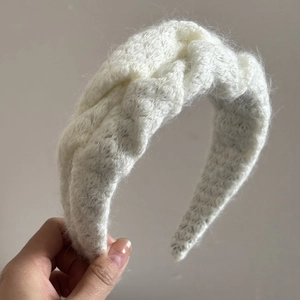 Primer plano de diadema de punto de trenzas blanca que muestra tela gruesa y textura suave