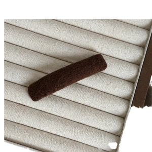 Brown fuzzy hair clip with plush wool texture on a minimalist jewelry display tray