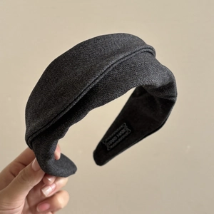 Gros plan du bandeau en tweed gris foncé torsadé avec une étiquette Hand Made