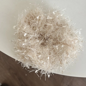 Detail of a fluffy cream-colored plush scrunchie with soft feather-like textures