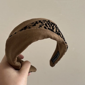 Détail d'un serre-tête large en tissu marron foncé avec un empiècement à motif léopard