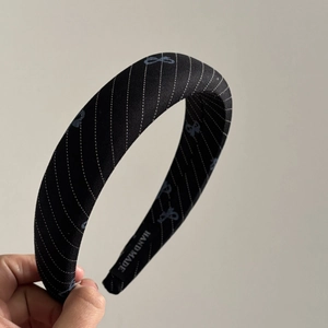 Close-up of handmade wide headband featuring white polka dot stripes and blue bow patterns