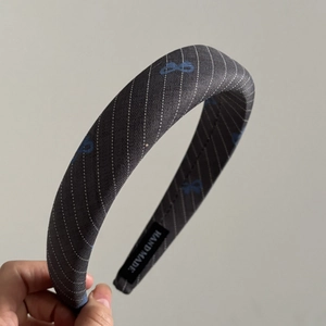 Detailed macro of a wide striped headband with blue bow patterns and handmade label