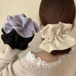 Détail de chouchous géants en tissu à volants de couleurs violette, noire et beige