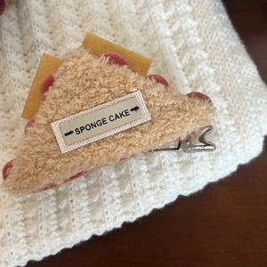 Cute cream sponge cake plush hair clip for women with red wavy edges on white knit background