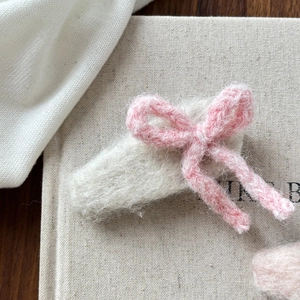 Gros plan sur une pince à cheveux avec nœud en tricot rose et base en peluche blanche