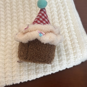 Detail of plush cupcake hair clip with cream fur, colorful sequins and a plaid hat accessory