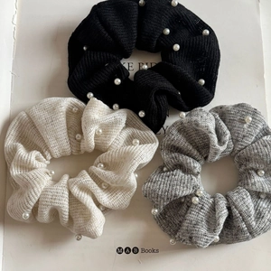 Three-piece set of knit pearl scrunchies in black, cream, and grey marl with elegant texture