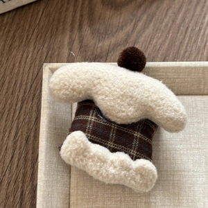 Detailed macro view of handmade plaid knitted hair clip with white faux fur and pompom trim