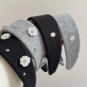 Detail of wool fabric headband with flower sequins, rivets and metal believe tag