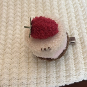 Detail shot of a plush strawberry cream cake hair clip with soft fuzzy texture and metal grip
