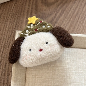 Detailed macro view of a handmade plush dog hair clip with a green Christmas tree hat