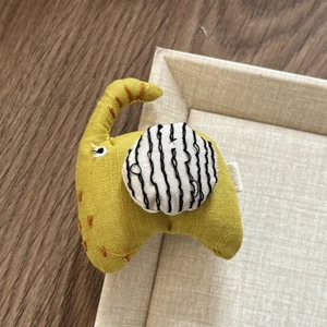 Detailed view of a handmade yellow fabric elephant hair clip with creative orange stitching