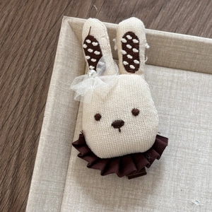 Detail of handmade rabbit hair clip with beige cotton fabric and lace pearl bow