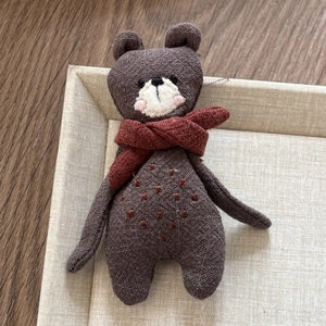 Detailed close-up of handmade brown fabric bear hair clip with a red scarf on a tray