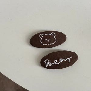 Detail of sweet bear embroidery and text on brown fabric hair clips set for women