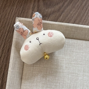 Close-up of handmade fabric rabbit hair clip with floral ears and small gold bell detail