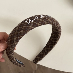 Detail view of brown plaid headband with white bear embroidery and handmade woven label