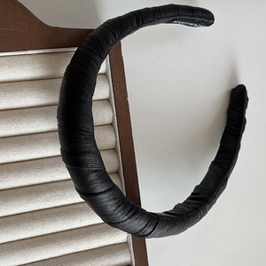 Vue détaillée du serre-tête en cuir noir avec plis souples et inscription faite à la main