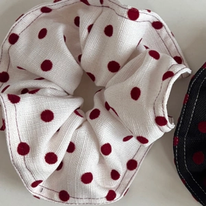 Detailed close-up of white fabric scrunchie with red polka dots and waffle texture
