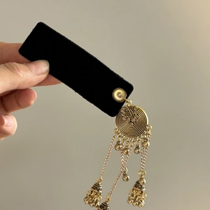 Detailed close-up of vintage golden ethnic tassels and bells on a velvet hair clip accessory