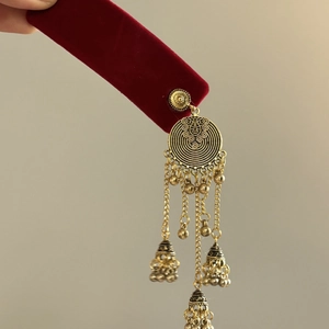 Vintage gold ethnic fringe earrings with jhumka bells on red velvet display card
