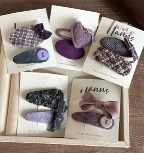 Détails de diverses barrettes à nœuds en tweed et velours violets sur carte blanche