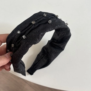 Close-up of black metallic fabric headband featuring sparkling rhinestone embellishments